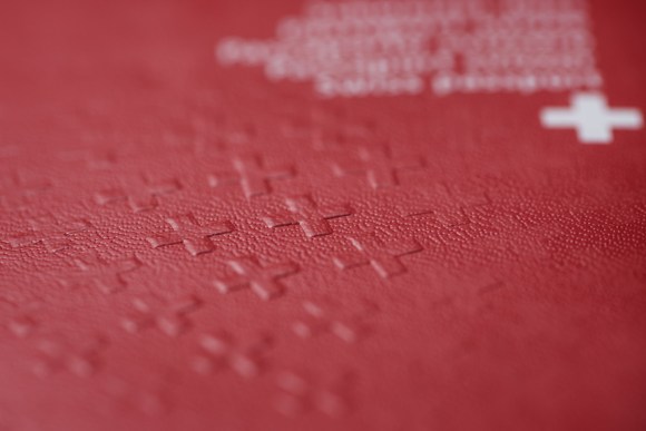 Immagine macro della superficie di un passaporto svizzero: si vedono bene le croci in rilievo e intravvede la scritta