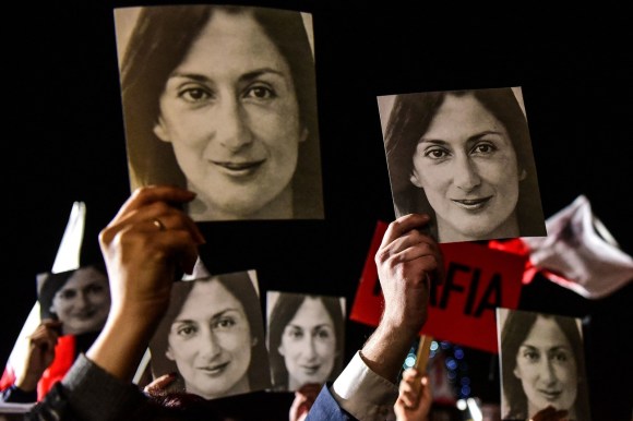 mani che tengono dei cartelloni raffiguranti il volto di una donna