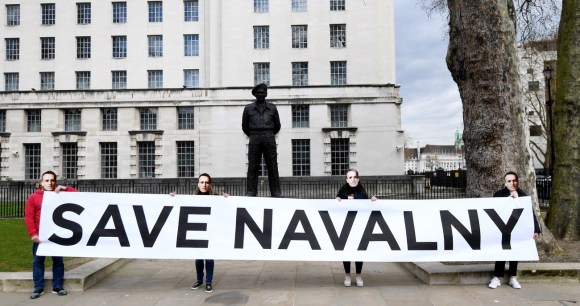 Un lungo striscione tenuto da quattro persone con la scritta Save Navalny