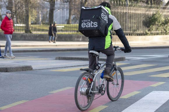 Un uomo in bicicletta con sulle spalle uno zaino per la consegna di cibo Uber eats.