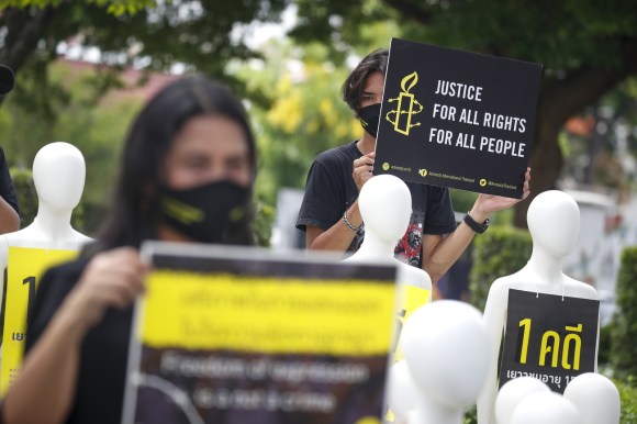 Manifestazione di persone con tratti asiatici, sfilano con cartelli con logo e slogan di Amnesty
