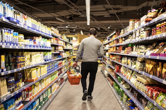 Un giovane cammina con la cesta in mano all interno di un supermercato.