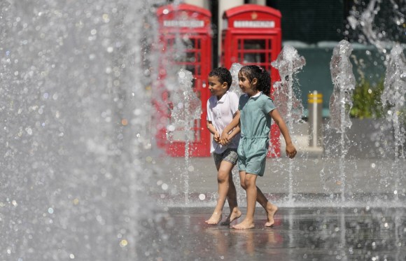 Un bambino e una bambina giocano a una fontana londinese.