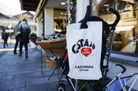 sacchetto con scritta Gstaad I love you appeso a una carrozzina per bebé di fronte a un negozio