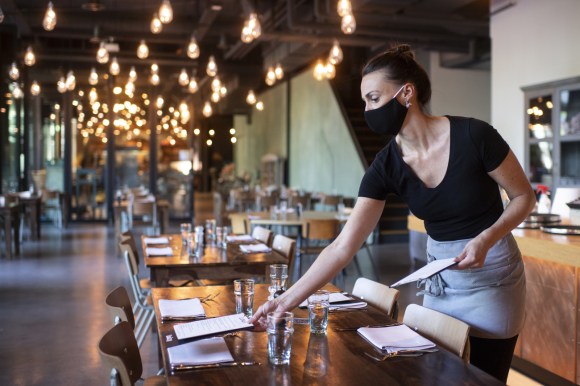 Una cameriera apparecchia i tavoli di un ristorante