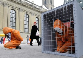 Menschen in orangen Anzügen in Käfigen
