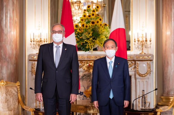 guy parmelin e yoshihide suga in posa per una foto davanti alle bandiere dei due rispettivi paesi