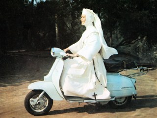 Debby Reynolds dressed as a nun riding a Vespa
