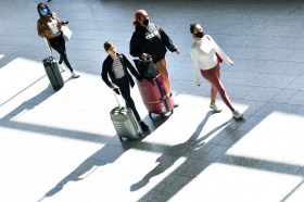 quattro persone in aeroporto con valigie al seguito fotografate dall alto