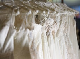 Una serie di vestiti da sposa appesi in fila sulle grucce.