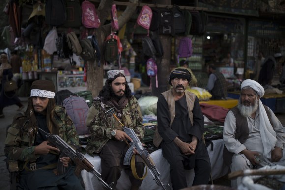 talebani armati seduti accanto a un venditore ambulante