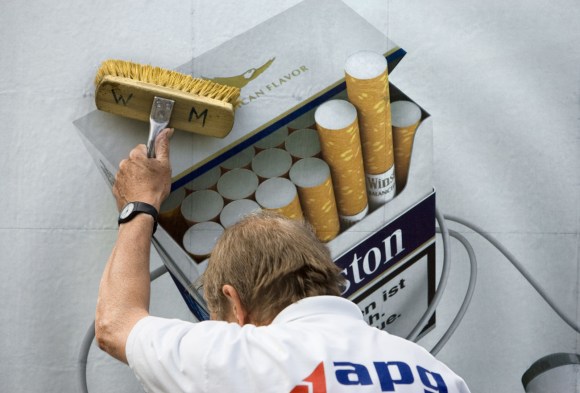 Un impiegato della Società di affissioni mentre appende una pubblicità su una marca di sigarette.