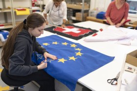 Due donne stanno cucendo le bandiere dell Ue e della Svizzera.