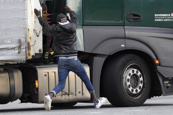 Un migrante cerca di salire su un camion in movimento