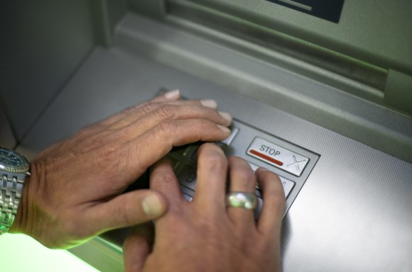 Una persona immette il codice a un bancomat