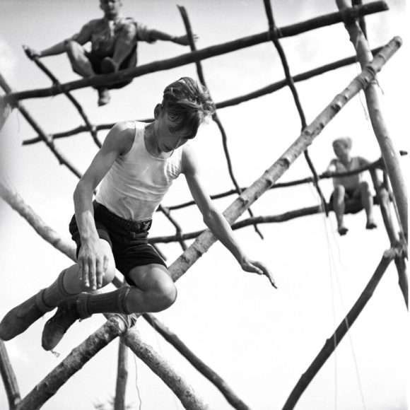 fotografia in bianco e nero di un ragazzino che salta da una struttura in legno. Fotografia d epoca