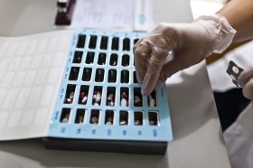 Una farmacista prepara le medicine giornaliere di un paziente in una scatola apposita.