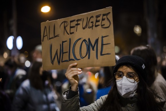 cartello tenuto da una donna con scritta in inglese tutti i rifugiati sono i benvenuti