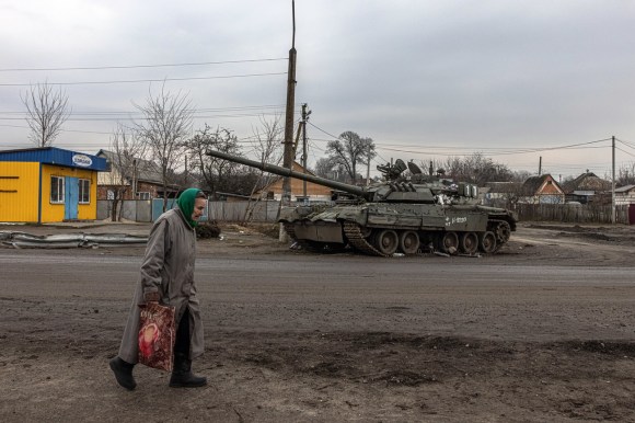 Una anziana donna ucraina passa davanti a un carro armato russo danneggiato.