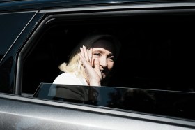 donna bionda saluta dal finestrino di un auto con vetri oscurati