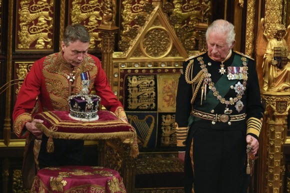 due uomini in abiti militari da cerimonia, uno di loro porta un cucino di velluto rosso sul quale è presente una corona reale