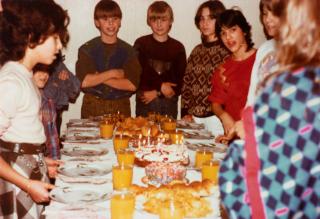 bambini attorno a un tavolo su cui c è una torta di compleanno