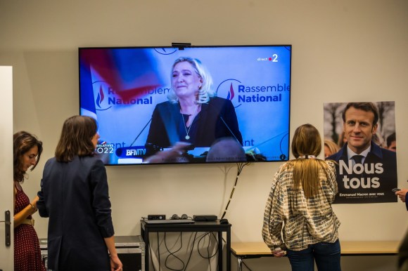 schermo di televisione con immagine di Marine Le Pen e poster con immagine di Emmanuel Macron