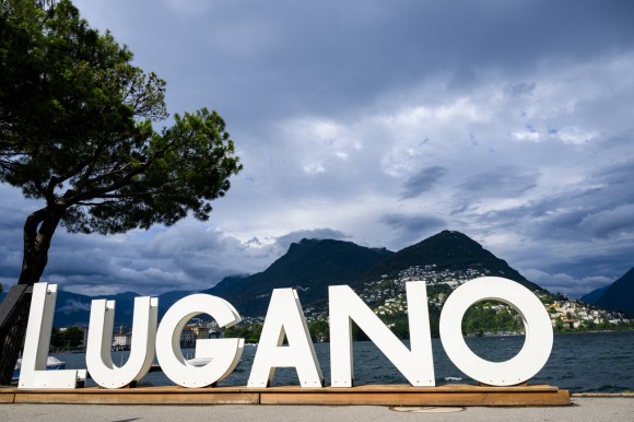 cartellone con la scritta Lugano con lago e montagna sullo sfondo