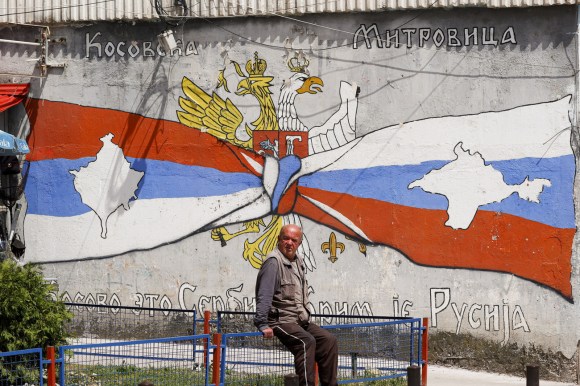 uomo davanti a un graffiti raffigurante una bandiera