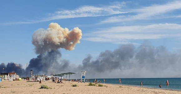 Una spiaggia vicina alla base russa: si vede un nuvolone di fumo.