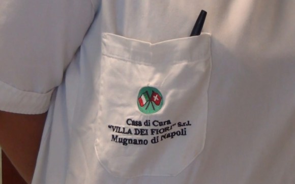 camice di un medico con un logo con le bandiere svizzera e italiana.