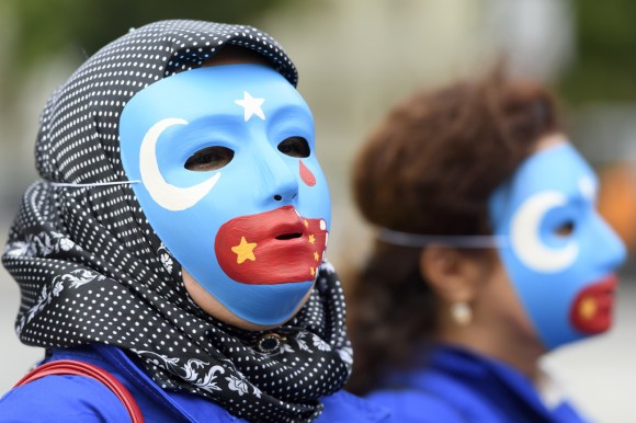 Due persone con maschere uigure protestao in Piazza Federale a Berna.