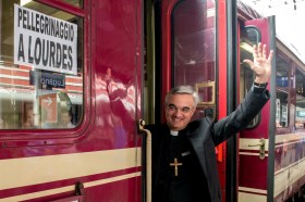 Il vescovo Lazzeri mentre sale sul treno diretto verso Lourdes.