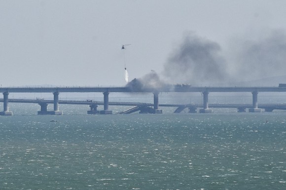ponte dal quale sale fumo ed elicottero che getta acqua sulle fiamme