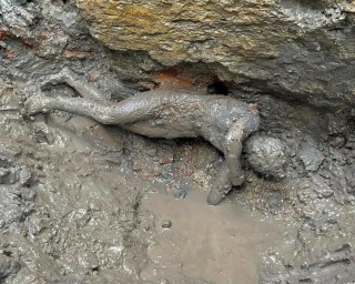 Una statua di un giovane ancora nel fango.