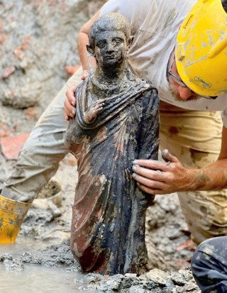La figura di un giovane che esce dal fango tenuta da uno studioso.