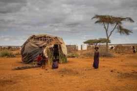 delle donne accanto a una capanna di legno in un paesaggio arido in africa