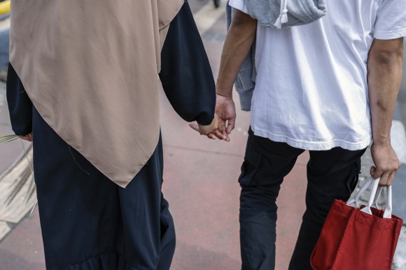 coppia che cammina per strada mano nella mano. fotografati di spalle, non si vedono i loro volti.