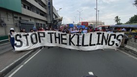 corteo di persone con, di fronte, striscione con scritta stop the killings
