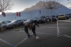due ragazzi giocano a calcio su un parcheggio