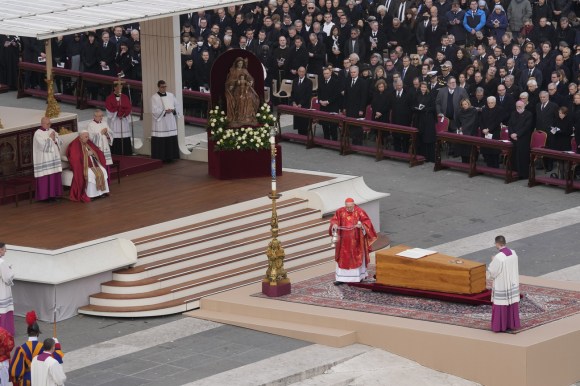 fotografia dall alto della bara, due sacerdoti e papa francesco che osserva