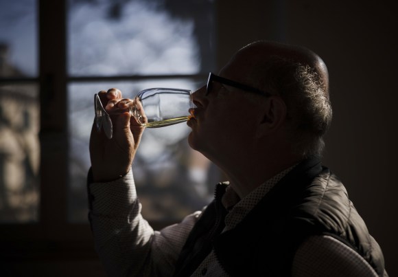 Un uomo nell ombra assaggia un vino bianco.