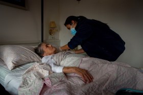 infermiera somministra cure a donna anziana sdraiata in un letto