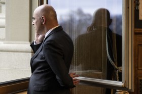 Alain Berset mentre parla al telefonino davanti a una finestra aperta di Palazzo Federale.