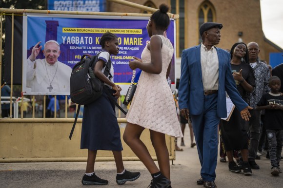 persone davanti a un manifesto con la foto del Papa