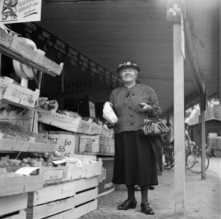 Donna accanto a uno stand di verdura