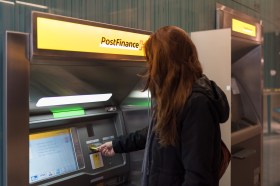 Donna preleva contanti dal bancomat di PostFinance