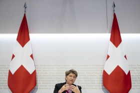 donna con a fianco due bandiere svizzere