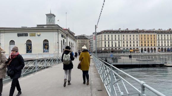 Two women walking away on a bridge over a river