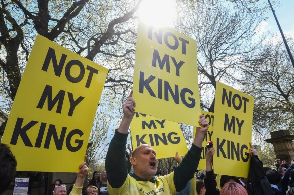 persone che tengono in mano cartelli gialli con scritta nera NOT MY KING (non il mio re)